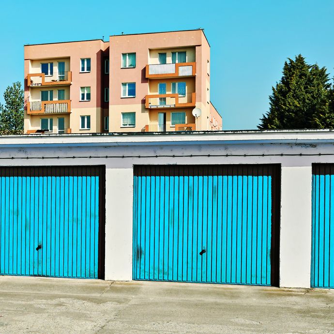 Garages with blue doors and buildings behind