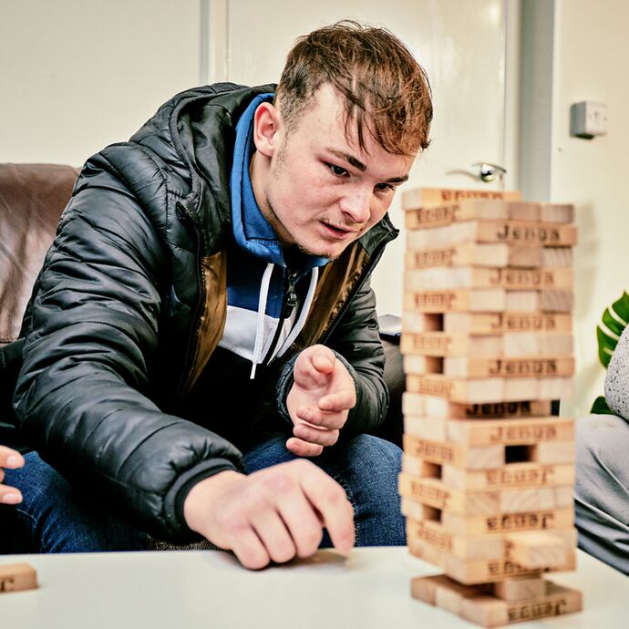 A young male reaches out to remove a piece from a tower puzzle