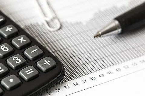 A calculator, a pen and a paperclip resting on paper showing a graph