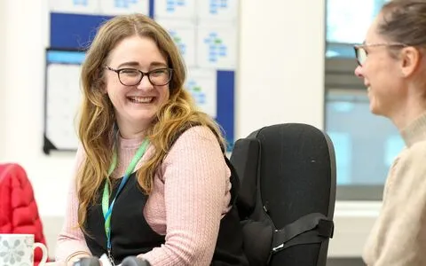 Two smiling women chatting to each other.