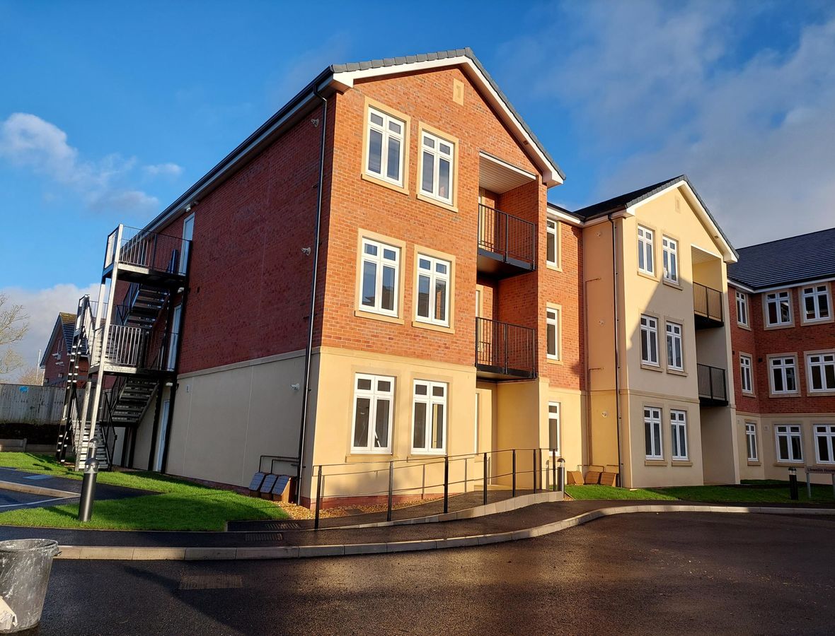 Brick built apartment block with a tarmac road running next to it