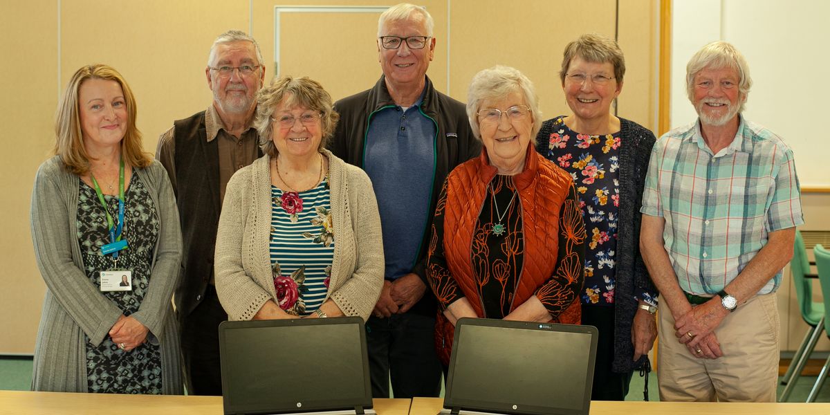 The GOAL group and Emma Johns from Connexus standing in front of two donated laptop computers 