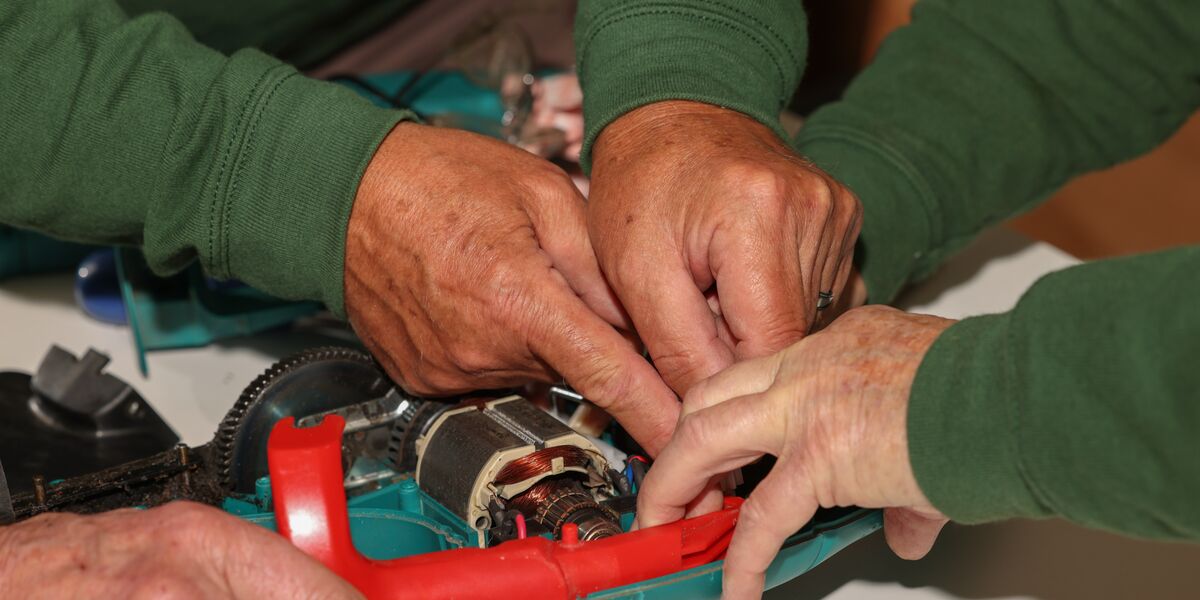 Volunteers hands mending an electronic device 