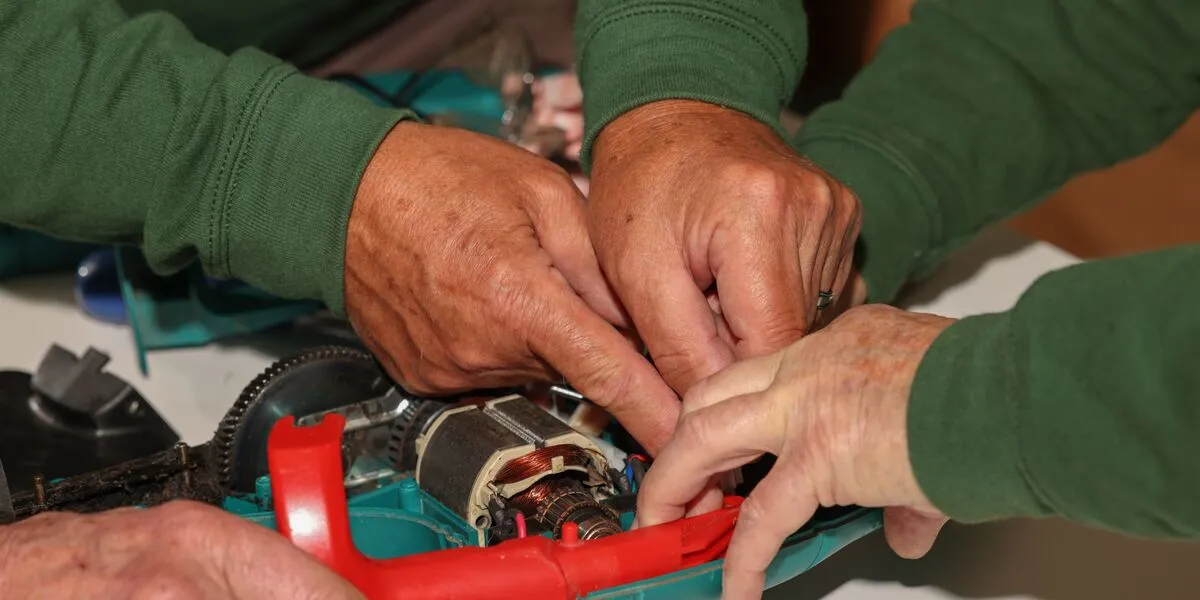 Volunteers hands mending an electronic device 