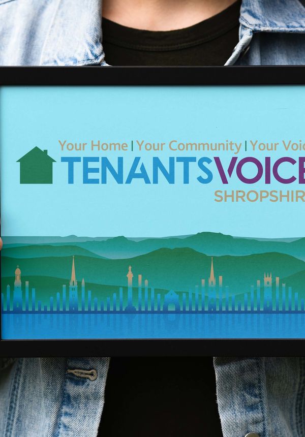 A person holds a picture frame containing the Tenants Voice logo