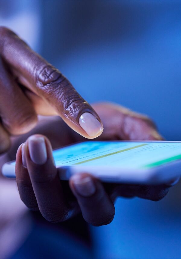 A hand holding a smartphone, with a finger about to press on the screen