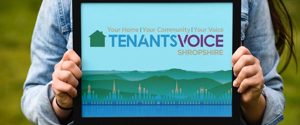 A person holds a picture frame containing the Tenants Voice logo