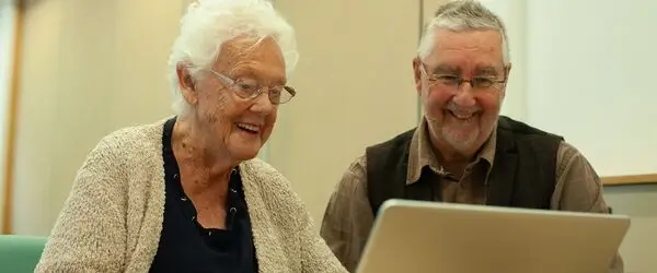 A learner from the GOAL group uses a laptop computer with guidance from one of the instructors. 