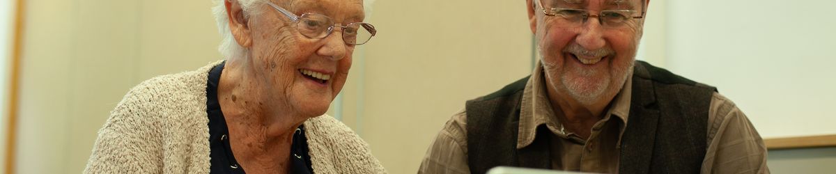 A learner from the GOAL group uses a laptop computer with guidance from one of the instructors.